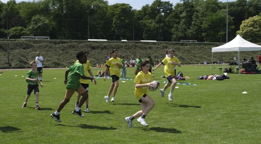 Les collégiens jouant au rugby sur la pelouse