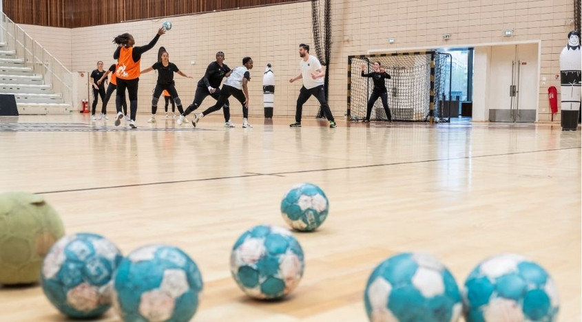 ballons de handball en premier plan sur terrain et joueurs en fond