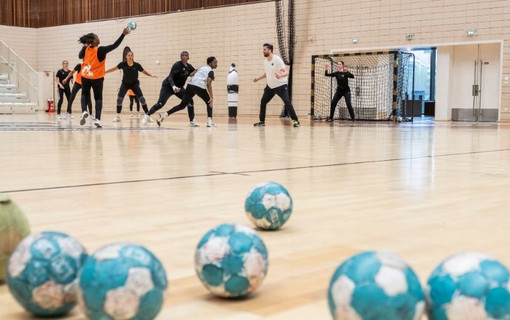 ballons de handball en premier plan sur terrain et joueurs en fond