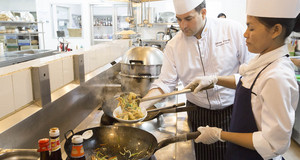 un chef et une cuisinière prépare un plat dans une cuisine 
