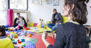 Puéricultrices avec des tout-petits avec des jeux, dans une grande salle lumineuse