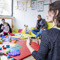 Puéricultrices avec des tout-petits avec des jeux, dans une grande salle lumineuse