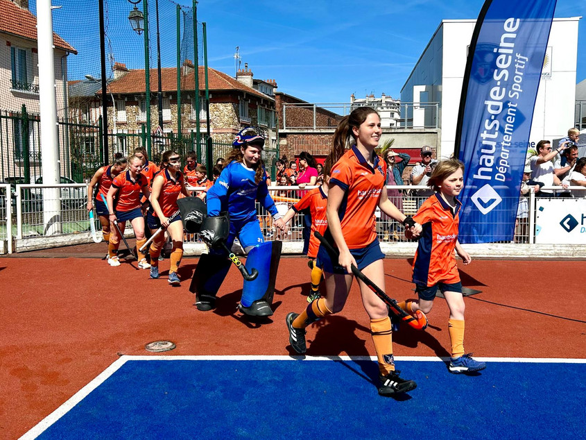 Jeune qui entre sur le terrain avec une des joueuses pro