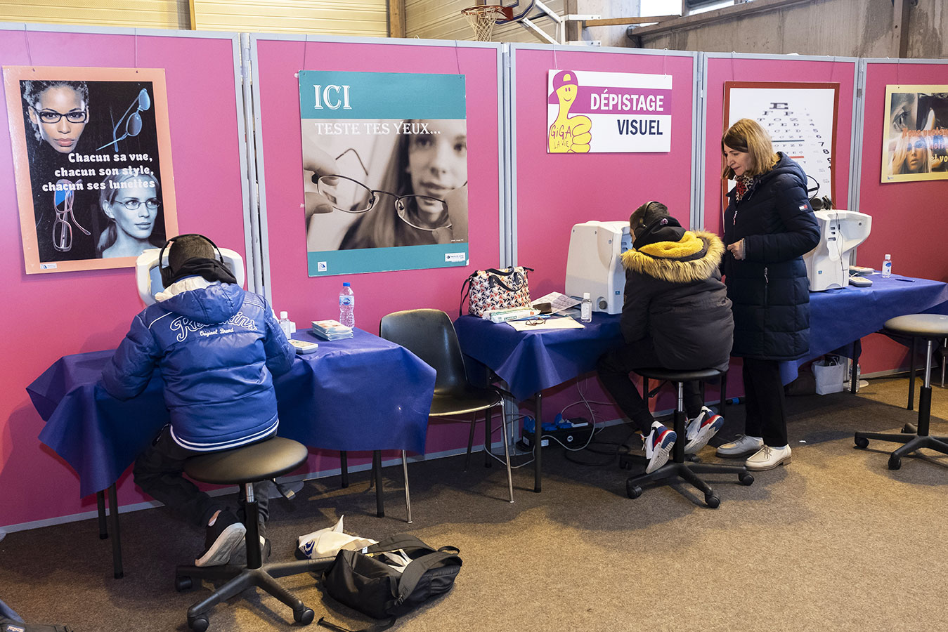Forum Giga la Vie Jeunes assis de dos devant des stands de dépistage santé, dans le hall du gymnase Pierre Bérégovoy de Châtenay-Malabry